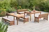 A wooden garden furniture set with benches and tables on a paved patio, surrounded by plants and flowers. Produktbild-Vorschau