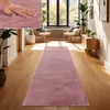 A hallway with a pink rug, chairs, and plants.