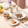 A table setting with a meal and fruit salad, featuring cherry blossom-themed tableware. Voir les images du produit