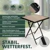 A square folding table with a wood-look top and black metal legs, shown outdoors on a patio. Anteprima dell’immagine prodotto