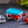A small glass container filled with cherry tomatoes, placed on a dark countertop. Produktbild-Vorschau