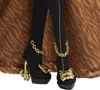 Close-up of a doll's legs wearing black stockings and high-heeled shoes with gold accents. Voir les images du produit