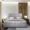 A luxurious bedroom scene featuring a large bed with a tufted headboard, bedside tables with lamps, and decorative wall paneling. Produktbild-Vorschau