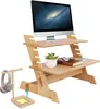 A wooden standing desk converter with a computer monitor, a plant, and a book. Produktbild-Vorschau
