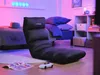 A gaming chair is placed on the floor in a room with colorful lighting. Náhľad obrázku produktu