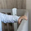 A close-up shot of a baby's hand holding onto the edge of a crib. Produktbild-Vorschau