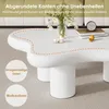 A white, irregularly shaped coffee table with decorative elements and text overlays. Produktbild-Vorschau