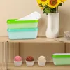 A product shot of ice cream storage containers and ice cream scoops on a shelf, with a vase of sunflowers in the background. Produktbild-Vorschau