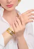 A woman's wrist wearing two stacked bracelets, one gold and one silver. Anteprima dell’immagine prodotto