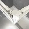 A close-up view of the corner joint of a white shower enclosure, showing screws and the white profile against a gray tiled wall and a white bathtub. Produktbild-Vorschau