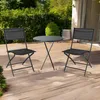 A black folding table and two chairs set on a wooden deck with greenery in the background. Voir les images du produit