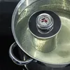 A thermometer is placed in a pot of boiling liquid. Produktbild-Vorschau