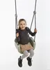 A young girl is sitting on a swing. Podgląd zdjęcia produktu
