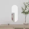 A mirror is displayed on a white wall above a wooden dresser. A plant in a glass vase is to the right of the mirror, and a small lamp is to the left. Podgląd zdjęcia produktu