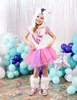 A young girl in a unicorn costume posing in a festive setting with balloons and confetti. Náhľad obrázku produktu