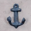 A black anchor-shaped wall hook mounted on a textured light gray wall. Produktbild-Vorschau
