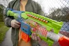 A person holding a Nerf toy gun outdoors. Produktbild-Vorschau