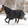 A horse wearing a black turnout blanket with gold trim runs through the snow. Voir les images du produit