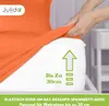 A hand is stretching an orange fitted sheet over a mattress. Produktbild-Vorschau