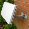 A white satellite dish is mounted on a brick wall next to green bushes. Produktbild-Vorschau