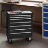 A black rolling tool chest with multiple drawers sits on a concrete floor in a workshop or garage setting. Produktbild-Vorschau