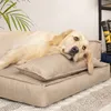 A golden retriever dog is resting on a beige dog bed with a small pillow. Produktbild-Vorschau