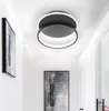 A modern LED ceiling light fixture with two circular rings, installed in a hallway with artwork on the walls. Produktbild-Vorschau