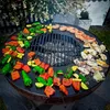 A round BBQ grill with various vegetables and seafood being cooked on it. Náhľad obrázku produktu
