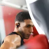 A man in a gym wearing black in-ear headphones. Produktbild-Vorschau