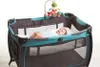 A baby lying in a playpen with a mobile above. Voir les images du produit