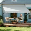 An elderly man reads a book under a light gray awning on a wooden deck, with a table and chairs set up. Produktbild-Vorschau