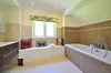 A clean and modern bathroom with a bathtub, window, and vanity. Produktbild-Vorschau