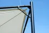 Close-up of a black metal frame and a white fabric canopy of a garden pavilion against a blue sky. Produktbild-Vorschau