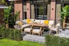 An outdoor patio set with a sectional sofa, dining table, and chairs, surrounded by greenery and a brick building. Produktbild-Vorschau