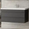 A modern bathroom vanity with a white countertop and a dark gray cabinet with two drawers, mounted on a tiled wall. Produktbild-Vorschau