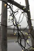 A close-up of a string of warm white LED lights wrapped around wooden poles. Podgląd zdjęcia produktu