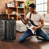 A man is playing an electric guitar in a living room, with a large speaker next to him. Produktbild-Vorschau