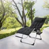 A black reclining lounge chair with a cushion and headrest is set up on a patio outdoors, with trees and greenery in the background. Produktbild-Vorschau