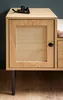 A close-up shot of a wooden shoe bench with a rattan door and a padded seat. Voir les images du produit
