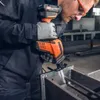 A person wearing work clothes and gloves is using a cordless reciprocating saw to cut through metal. Produktbild-Vorschau