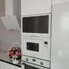 A modern kitchen with white appliances and a decorative basket of flowers. Produktbild-Vorschau