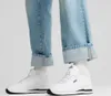 A close-up shot of a person wearing Puma sneakers and cuffed jeans. Produktbild-Vorschau