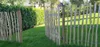 A wooden garden fence with wire accents is shown in a grassy yard next to a hedge. Anteprima dell’immagine prodotto
