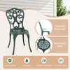 A green metal chair with decorative scrollwork, shown outdoors next to a white-paneled wall. Insets highlight the chair's inclined backrest and spacious seat, along with icons representing durability and weather resistance. Náhľad obrázku produktu