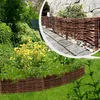 A garden scene with a wicker border around a flower bed and a pathway lined with a wicker fence. Produktbild-Vorschau