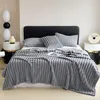 A neatly made bed with a grey blanket and pillows. Produktbild-Vorschau