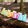 A line of colorful children's binoculars resting on a tree branch in a forest setting. Produktbild-Vorschau