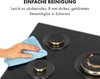 A hand is cleaning a black gas hob with a blue cloth. Produktbild-Vorschau