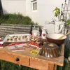 A table set up outdoors with baking supplies and cookies. Produktbild-Vorschau