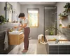 A woman is washing her hands at a sink in a modern bathroom with a bathtub and shower. Anteprima dell’immagine prodotto